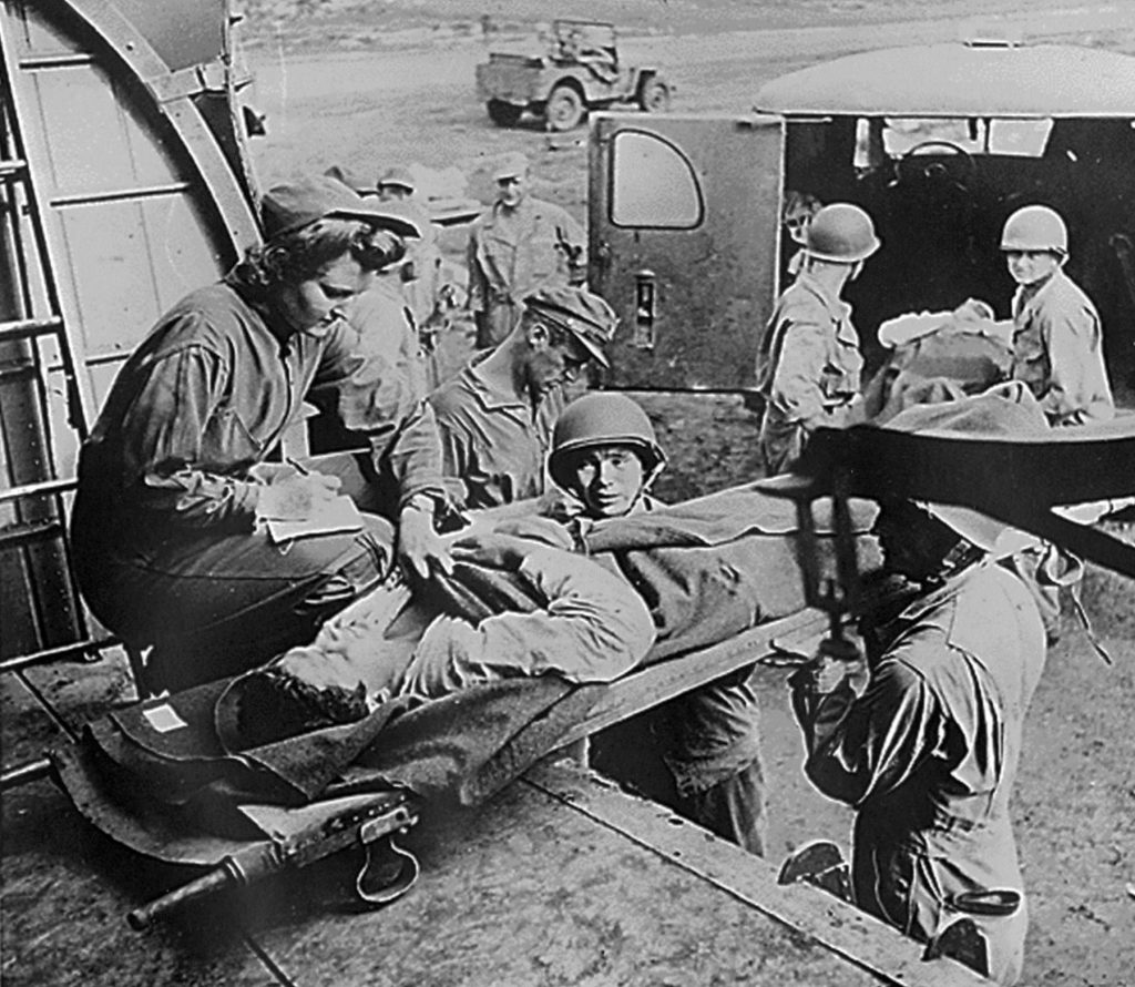 Flight nurse Lt. Mae Olson takes the name of a wounded American soldier being placed aboard a C-47 for air evacuation from Guadalcanal in 1943 (US Air Force photo)