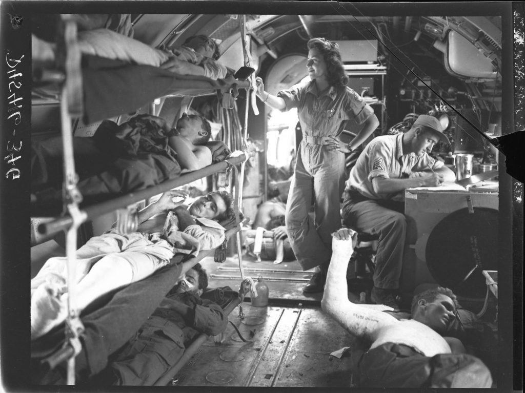 C-46 air evacuation from Manila, Philippine Islands, 1945—flight nurse standing, surgical technician at desk (US Army Air Force photo)