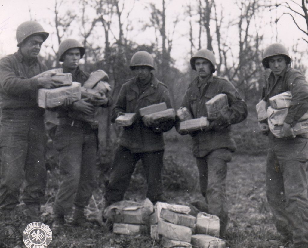 US Army Pfc. W.J. Kessler, Pfc. J.L. Proffitt, Pvt. B. Narter, Cpl. T.J. Barnewski, and Pfc. J. Stoll with Christmas packages from home for their artillery unit, Germany, 26 Nov 1944 (US Army Signal Corps)