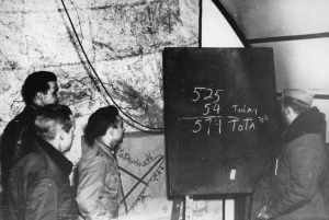 Colonel Dregne of the US 357th Fighter Group gives a briefing to pilots Foy, Storch and Evans at Leiston Army Air Field in England, 14 Jan 1945, showing the 54 victories earned by the group that day (later revised to 56.5 victories), and the group’s 549 total victories (Imperial War Museum, Roger Freeman Collection)