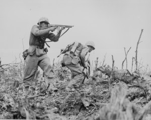 A Marine of the US 1st Marine Division pointed his Thompson submachine gun at a Japanese sniper, Okinawa, Apr-Jun 1945 (US National Archives: 127-N-123170)