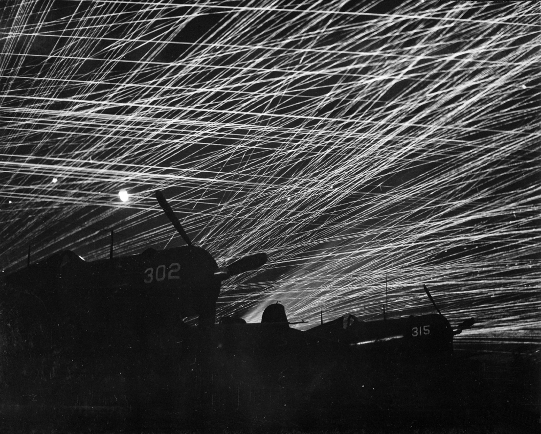 Anti-aircraft tracers in the night sky above Yontan Airfield, Okinawa, 28 Apr 1945; US Marine Corps F4U Corsair fighters in foreground (US National Archives: 127-G-118775)