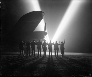 Ground crew on a RAF Bomber Command station in Britain return the ‘V for Victory’ sign to a neighboring searchlight crew. Silhouetted is the nose of a Lancaster bomber. (Imperial War Museum)