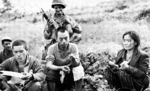 Japanese resistance fighters captured, Okinawa, Japan, Jun 1945; prisoner to the far left is reading American propaganda literature (US Army photo)