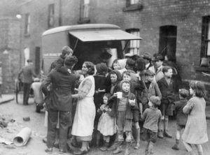 Mothers and children in a working class area of Swansea have tea and sandwiches from a mobile canteen after a night's bombing, WWII (Imperial War Museum: HU 36143)