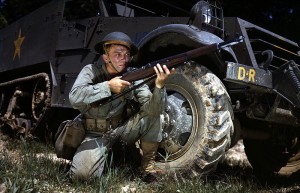 Infantryman in herringbone twill fatigues, kneeling in front of M3 half-track, holds and sights an M1 Garand rifle, Fort Knox, KY, June 1942 (Library of Congress: fsac 1a35212)