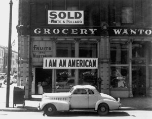 Sign posted in window of store owned by a Japanese-American the day after Pearl Harbor, shortly before the man's internment, Oakland, CA, March 1942 (Photo: Dorothea Lange, US National Archives)