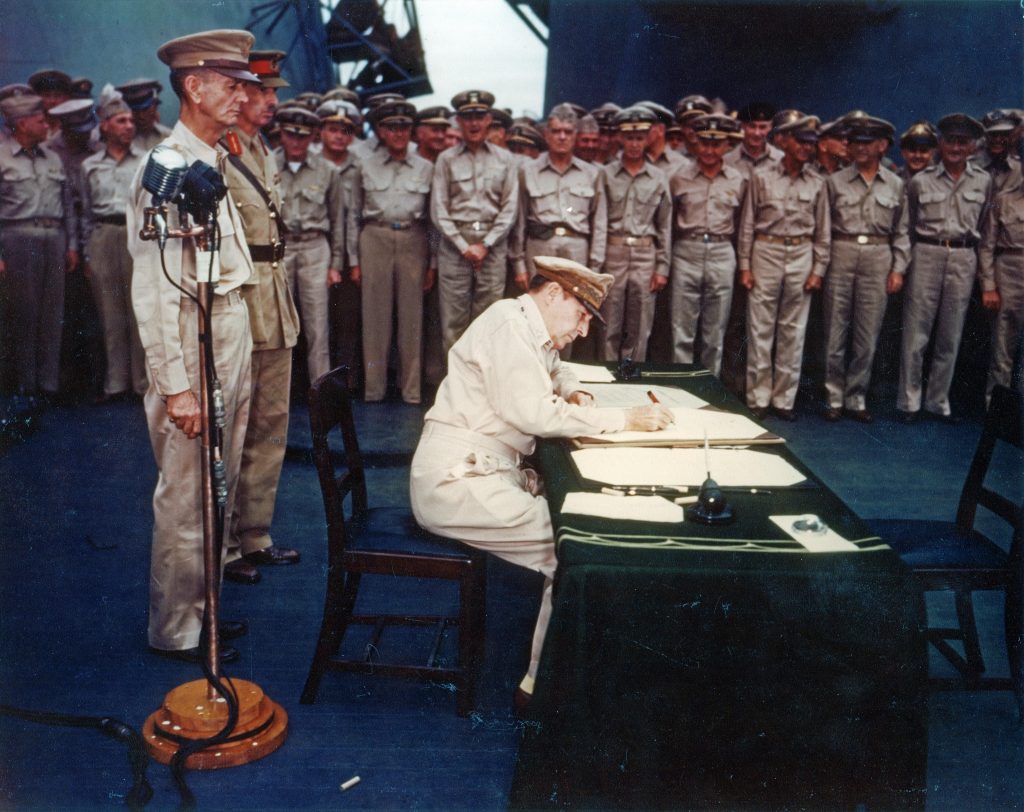 Gen. Douglas MacArthur signing the Japanese surrender documents aboard USS Missouri, 2 Sept 1945 (US National Archives)