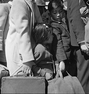 Japanese-American children waiting for bus to take them to an Assembly Center, Byron, CA, 2 May 1942 (US National Archives: ARC 537467)
