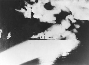 Heavy cruiser USS Quincy illuminated by Japanese searchlights during Battle of Savo Island, 9 Aug 1942 (public domain via WW2 Database)