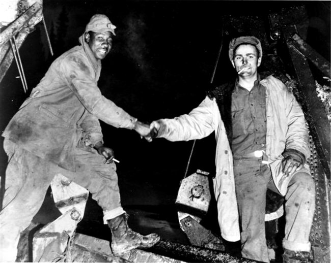 Cpl. Refines Sims Jr., left, and Pvt. Alfred Jalufkamet of the US Army Corps of Engineers meeting in the middle after completing construction of the Alcan Highway, 1942. (US Army Corps of Engineers photo)