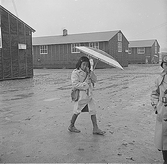 Japanese-American girl walking in rain, Jerome Relocation Center, AR, 12 Mar 1943 (US National Archives: ARC 539345)