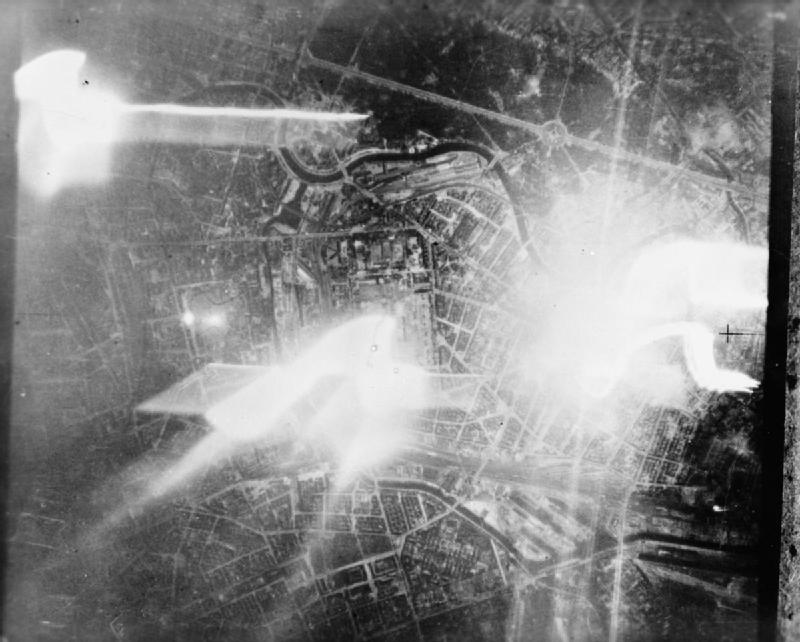 Berlin during a night raid by RAF Mosquitos; the track of a falling target indicator can be seen on the right, c. 1942-45 (Imperial War Museum)