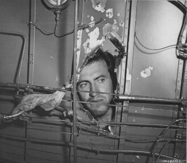 Lt. Louis Zamperini, bombardier, inspecting a hole in his B-24D Liberator, Superman, damaged over Nauru, 20 Apr 1943; photo taken at Funafuti in Gilbert Islands (US National Archives)