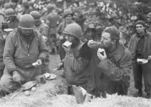 US troops eating Christmas dinner on a haystack, Italy, 25 December 1943 (US National Archives)
