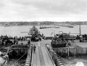 Military vehicles move ashore from Mulberry Artificial Harbor A, across a pontoon bridge, to Omaha Beach, Normandy, June 16 1944 (US National Archives)