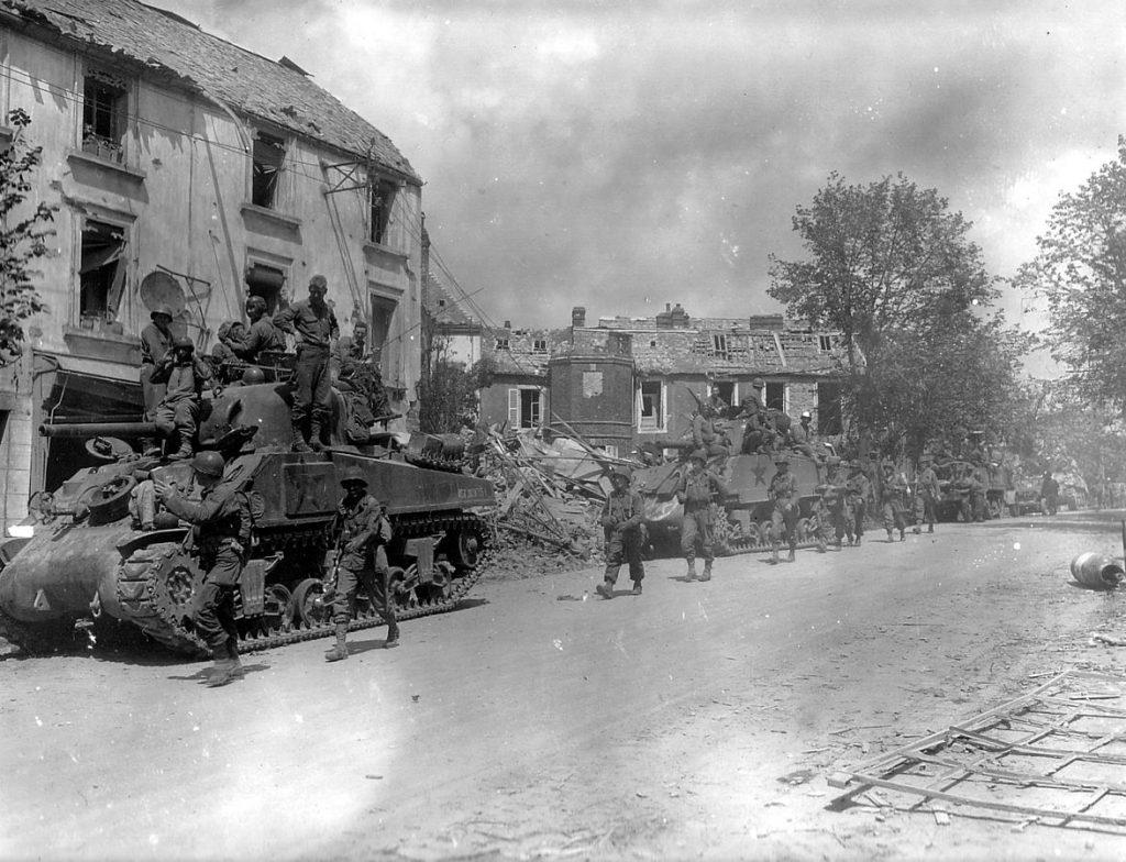 American armored and infantry forces pass through the battered town of Coutances, France, July 1944 (US National Archives)