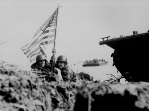 US officers plant flag eight minutes after troops begin landing on Guam, 21 July 1944 (US National Archives)