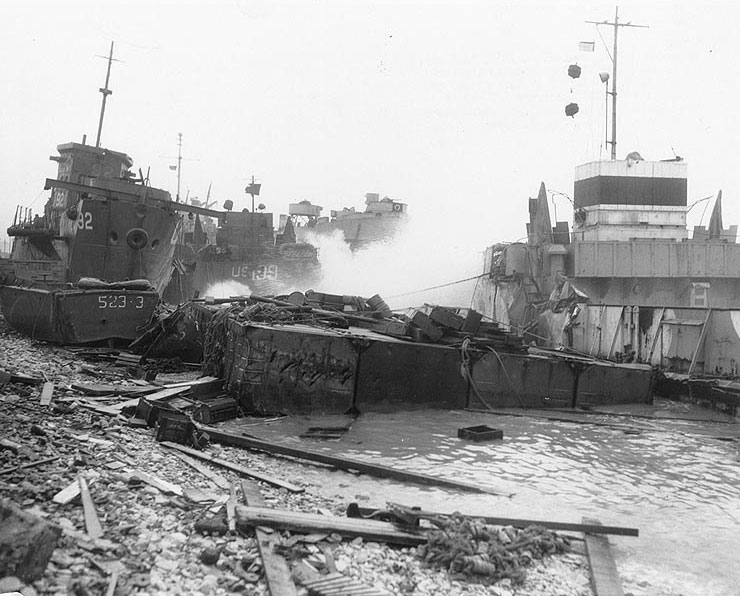 Broached landing craft during the Normandy storm, probably at Omaha Beach, 21 June 1944; USS LST-543 in background (US National Archives)