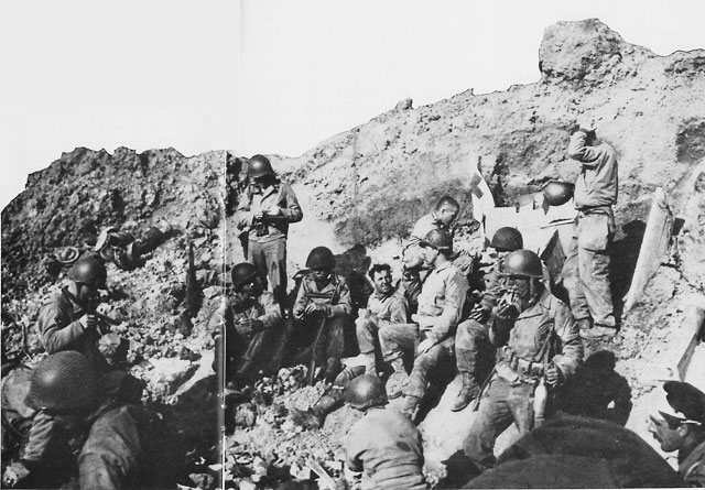 Pointe du Hoc, D-day, 6 June 1944: Lt. Col. James Rudder's Command Post was set in a cratered niche at the edge of the cliff. Lt. Eikner, in charge of the communications section, is near the center, drinking from his canteen (US Navy photo)
