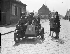 Belgian girls give flowers to British troops riding a Norton motorcycle combination in Herseaux, as the BEF crosses the border into Belgium, 10 May 1940 (Imperial War Museum: F 4344)