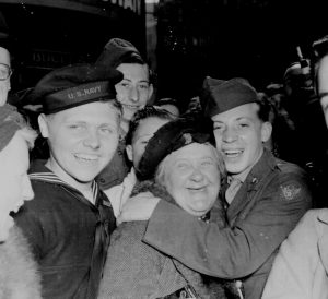 A jubilant American airman hugging an English woman at Piccadilly Circus, London, England, celebrating Germany's unconditional surrender, 7 May 1945 (US National Archives: 111-SC-205398)