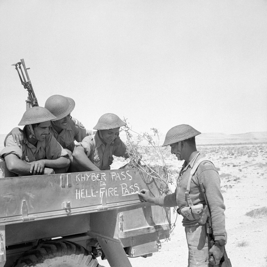 Troops of Indian 4th Division decorating their truck with “Khyber Pass to Hellfire Pass,” noting their service in South Asia and North Africa, 21 Jun 1941 (Imperial War Museum: E 3660)